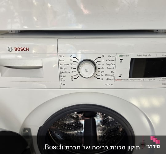 תקריב של מכונת כביסה לבנה עם פתח חזית ודלת פתוחה